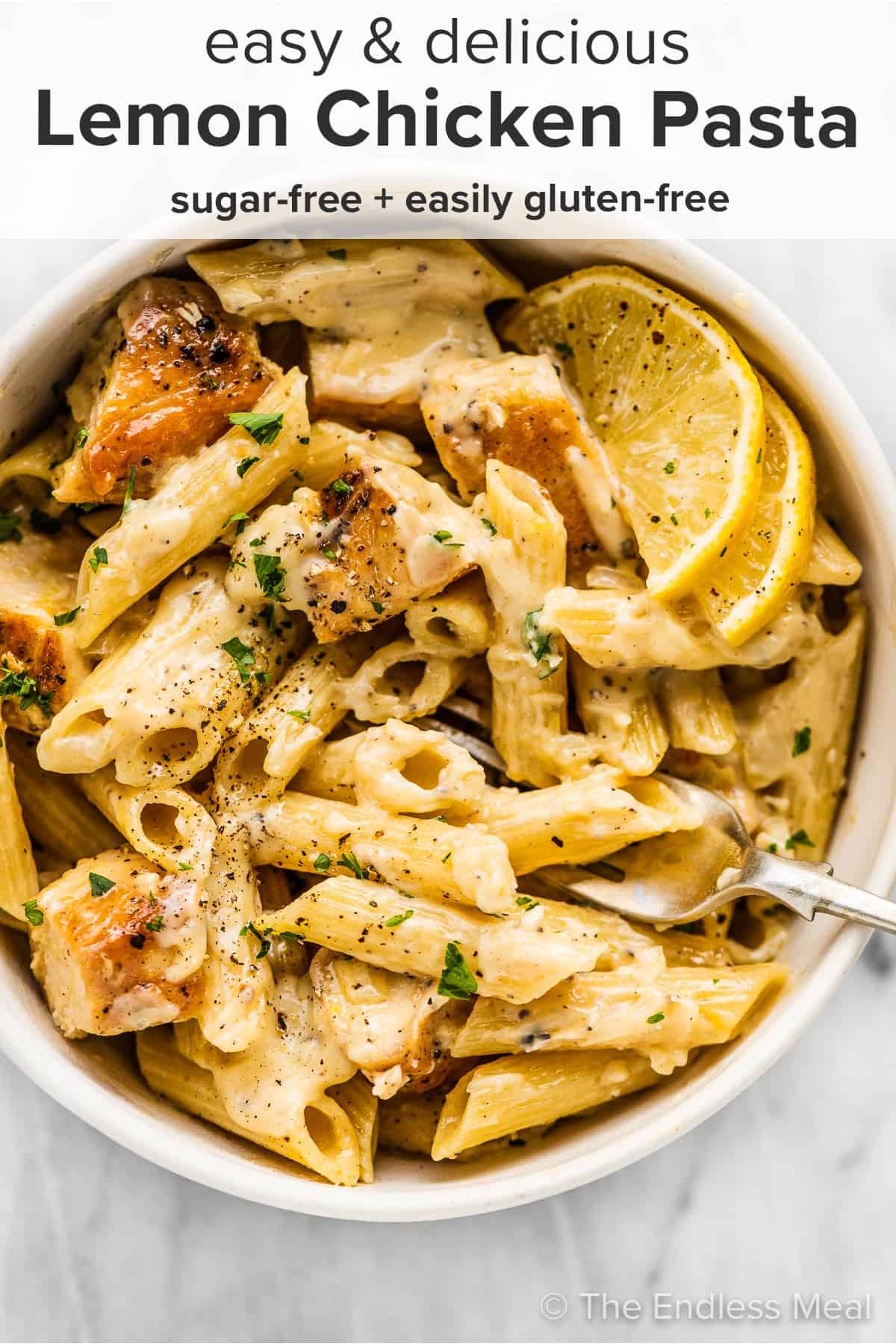 Lemon chicken pasta in a white bowl with a fork and the recipe title on top of the picture.
