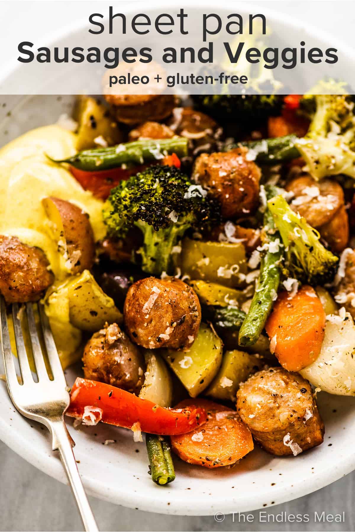 A closeup of sheet pan sausages and veggies in a dinner bowl with the recipe title on top of the picture.