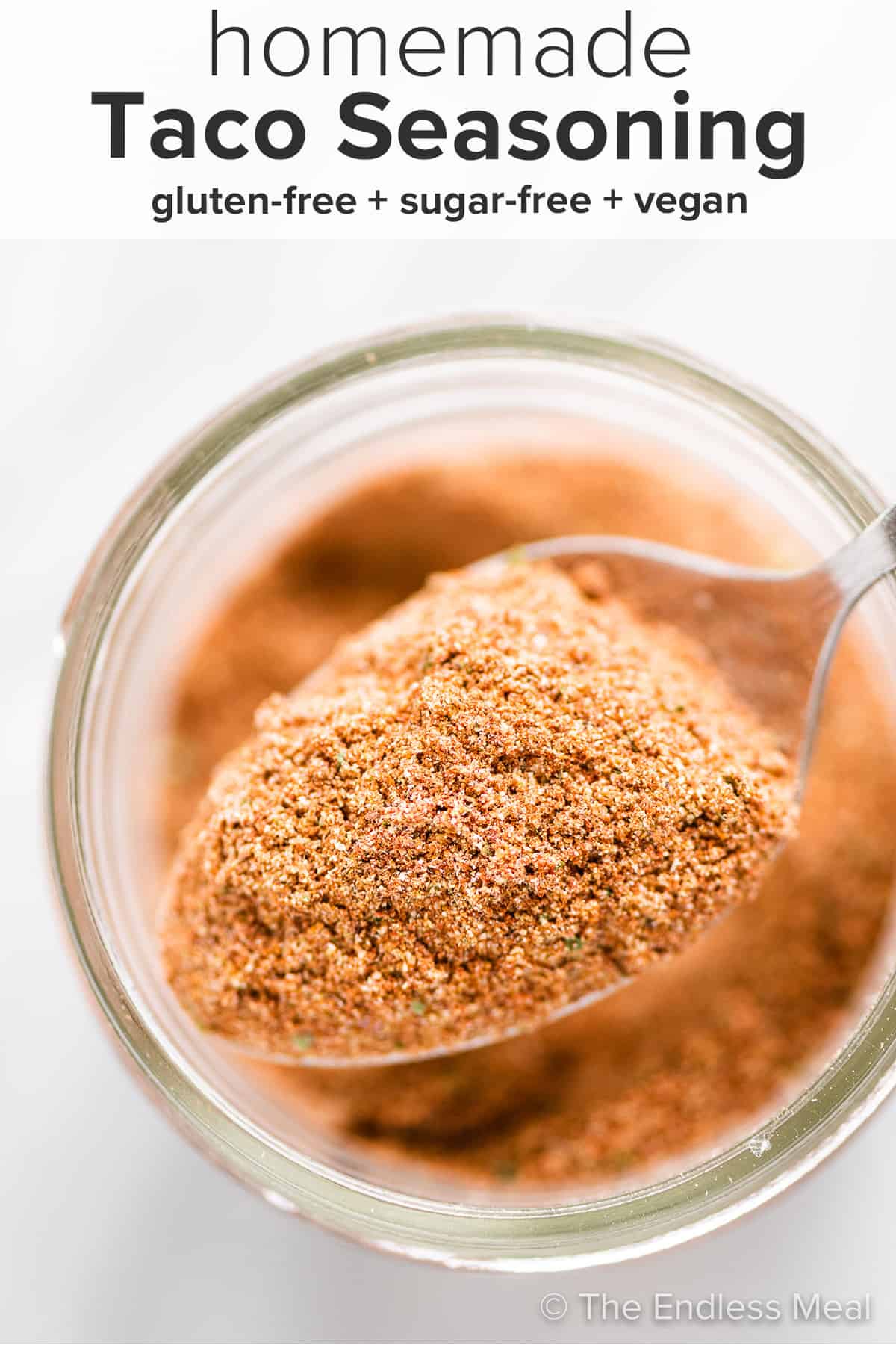 Looking down on a spoonful of homemade taco seasoning with the recipe title on top of the picture.