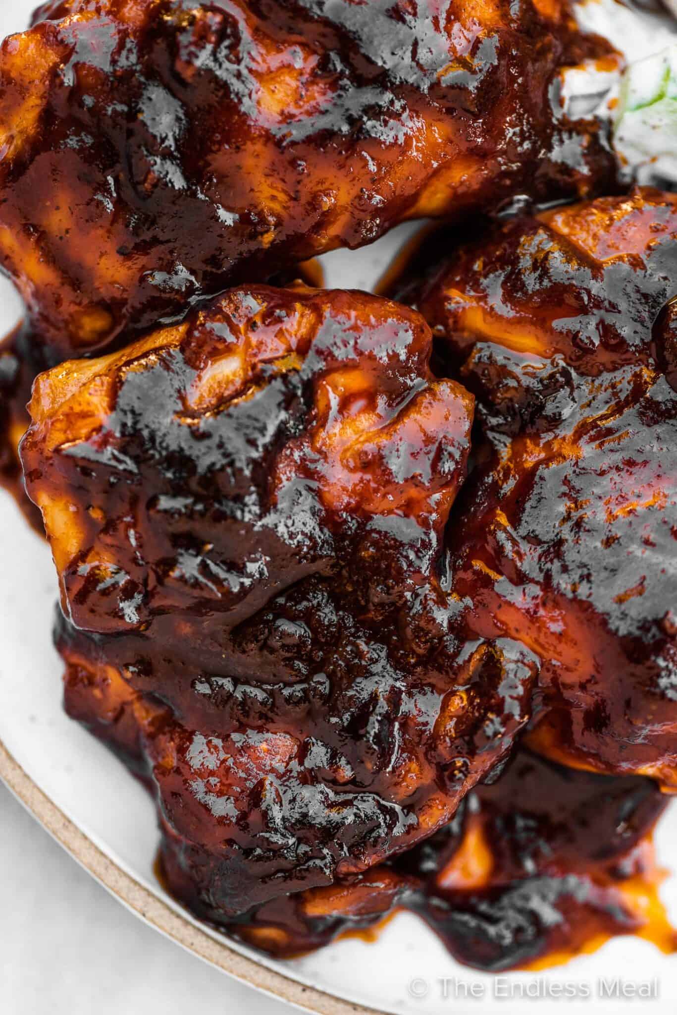 A close up of stovetop BBQ chicken covered in sauce on a plate.