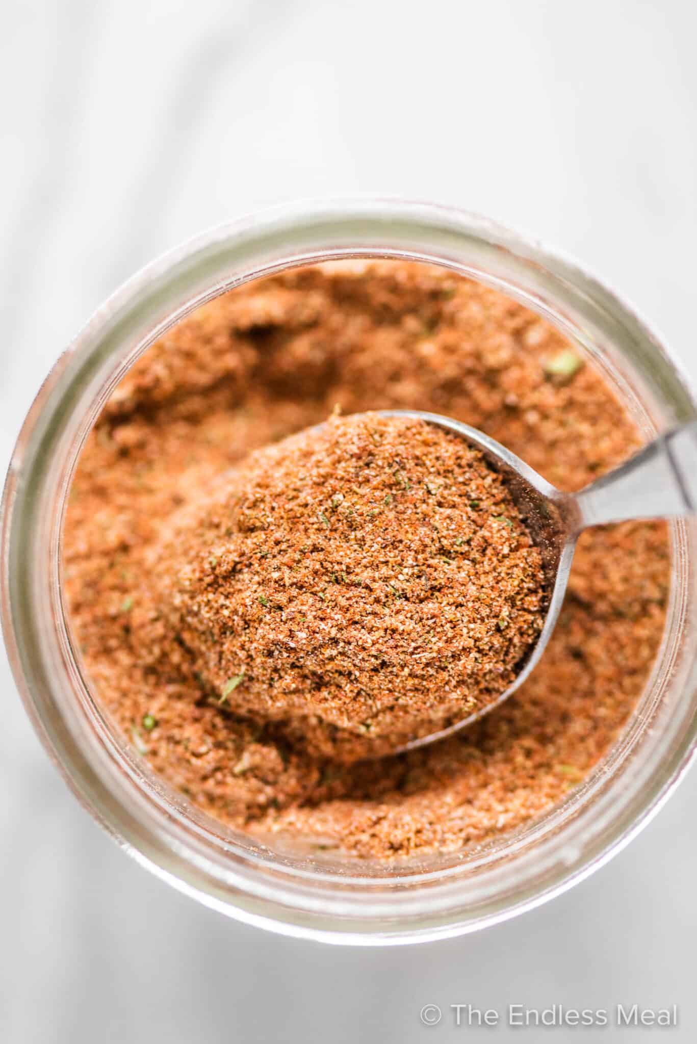 A spoon scooping some taco seasoning out of a jar.