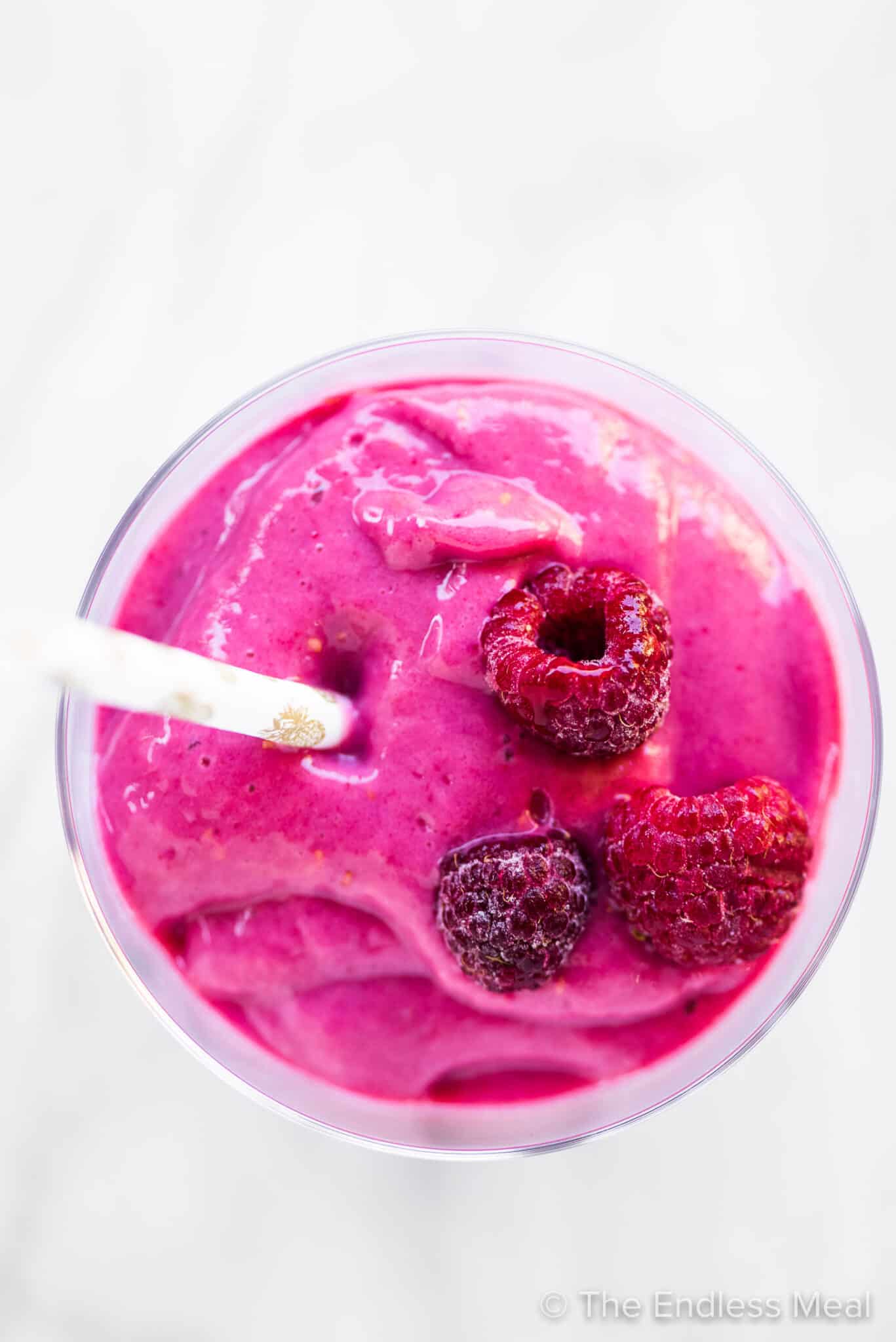 A bright pink tofu smoothie with berries on top.