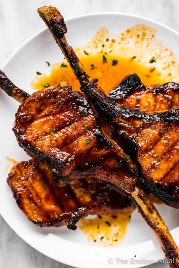 Oven grilled tomahawk pork chops piled on a white plate.