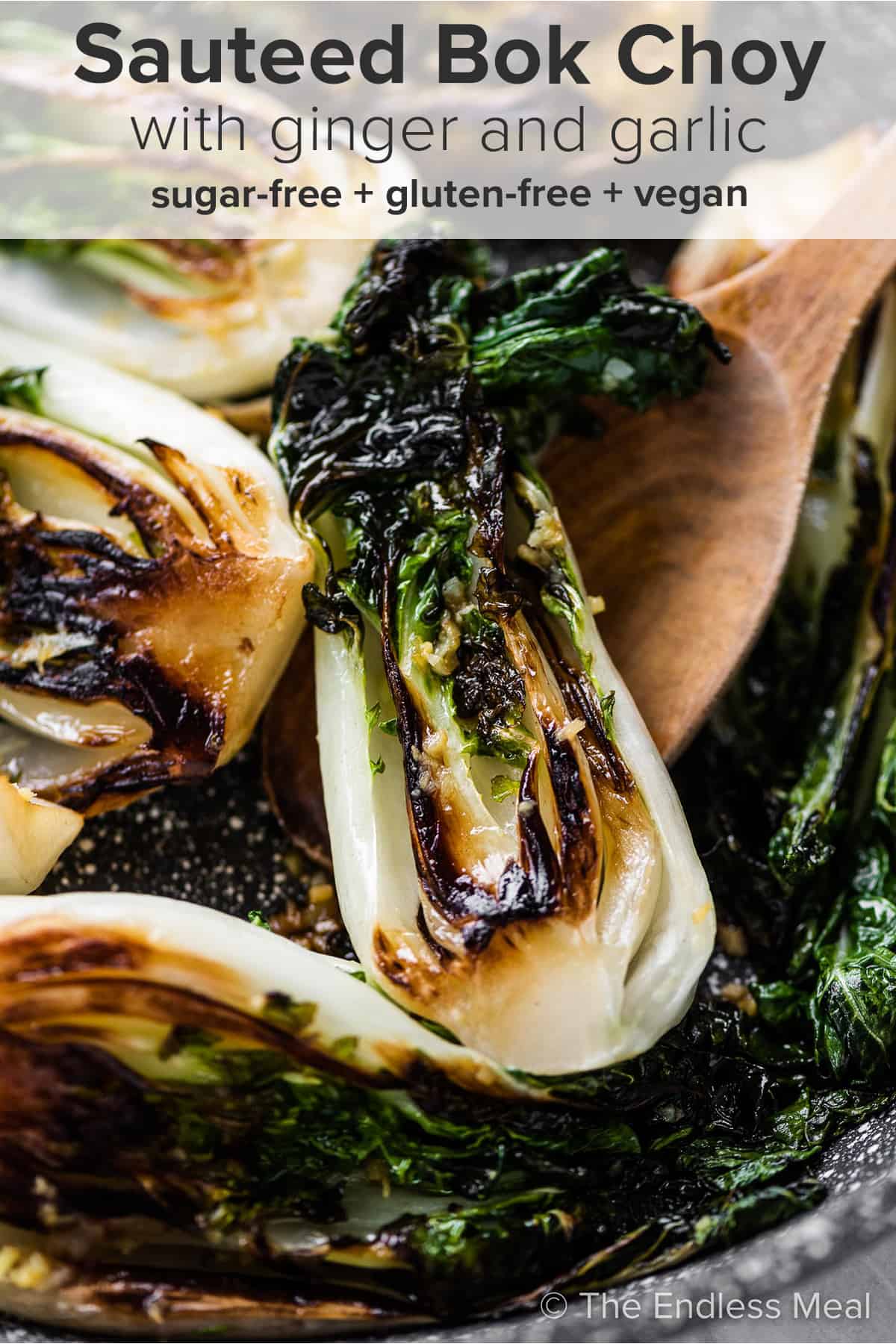 A wooden spoon lifting Sautéed Bok Choy with ginger and garlic out of a pan and the recipe title on top of the picture.