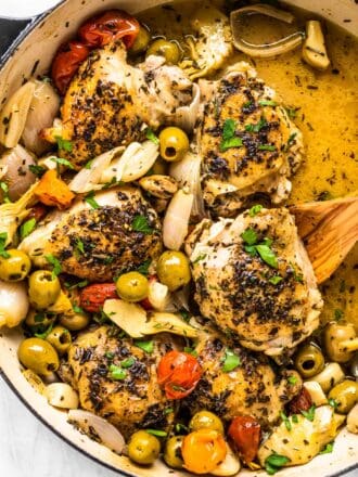 Chicken provencal in a braising pan with a wooden spoon.