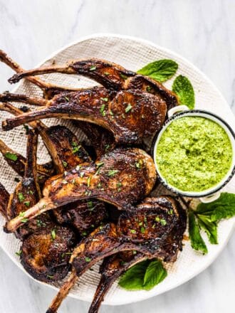 A plate piled with lamb lollipops with mint pesto on the side.