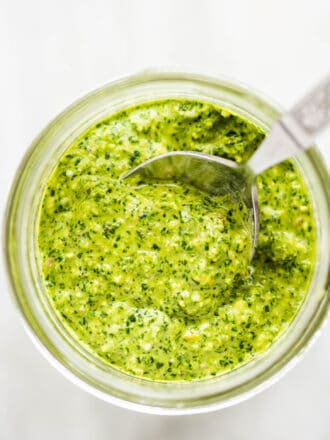 Mint pesto in a glass jar with a spoon.