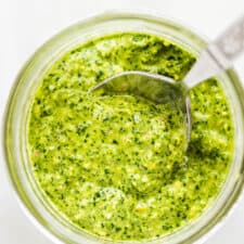 Mint pesto in a glass jar with a spoon.