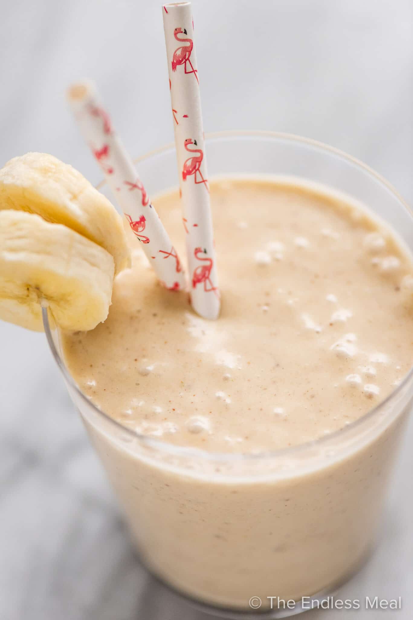 A Peanut Butter Banana Smoothie in a cup with straws.