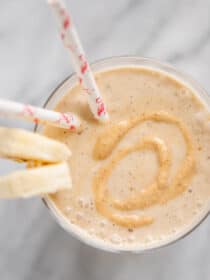 Looking down on a cup of Peanut Butter Banana Smoothie with banana slices on the side.