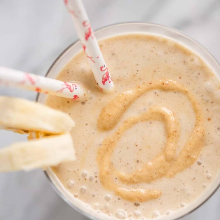 Looking down on a cup of Peanut Butter Banana Smoothie with banana slices on the side.