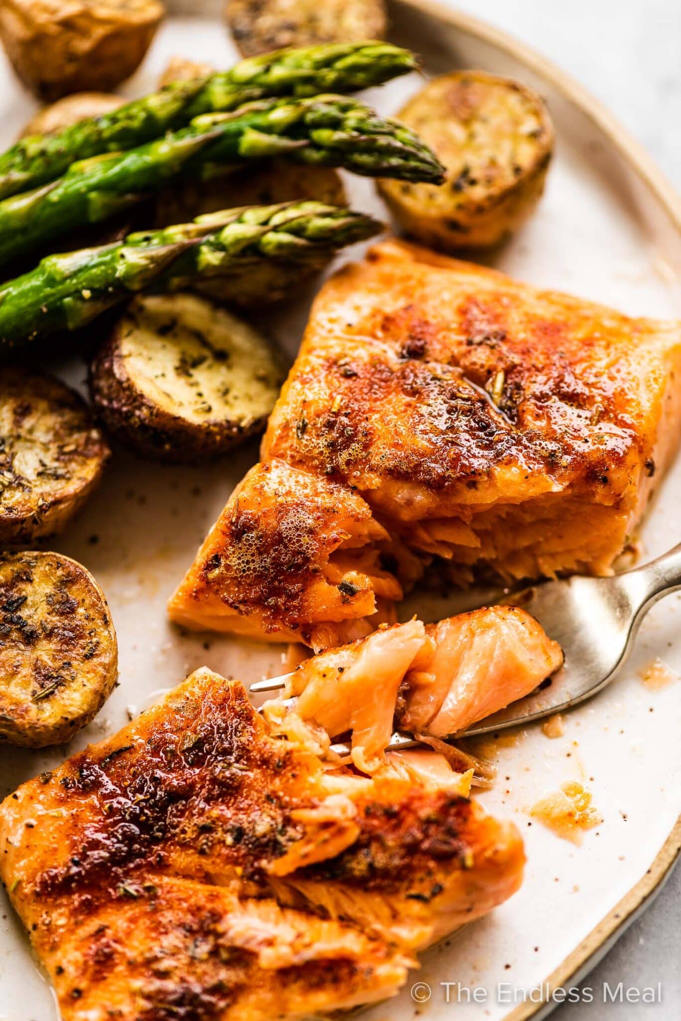 A dinner plate with sheet pan salmon, crispy potatoes, and asparagus.