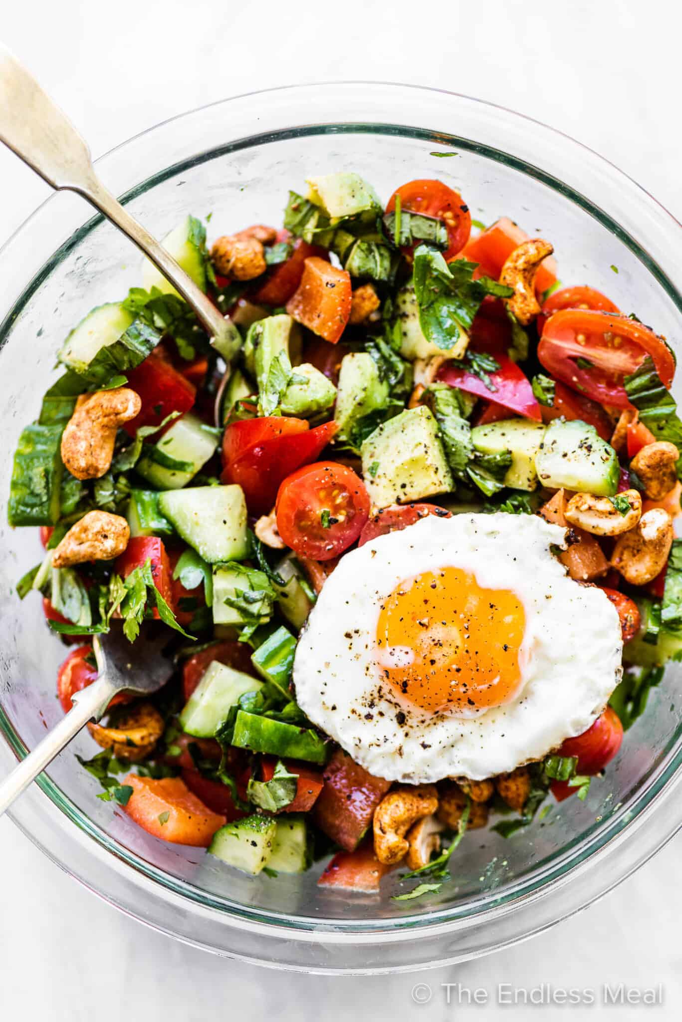 Healthy breakfast salad in a glass mixing bowl with an egg on top.