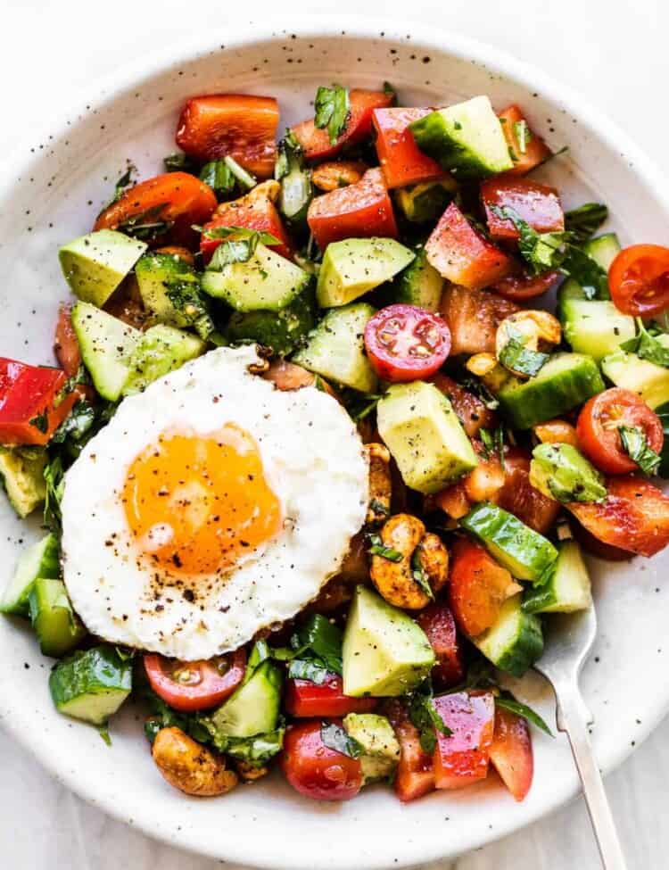 Healthy Breakfast Salad in a white bowl with a fried egg on top.