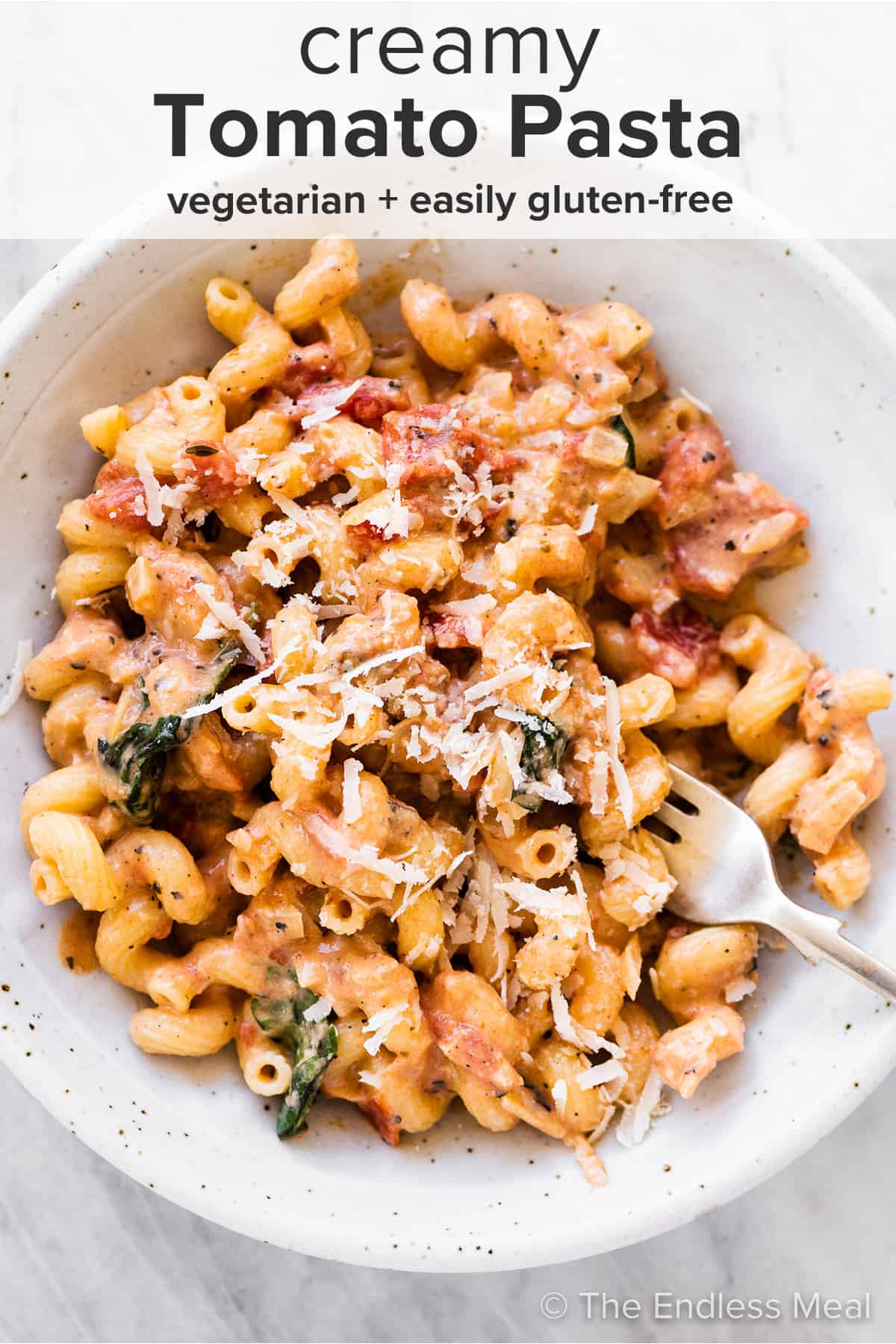 A bowl of Creamy Tomato Pasta with a fork inside and the recipe title on top of the picture.