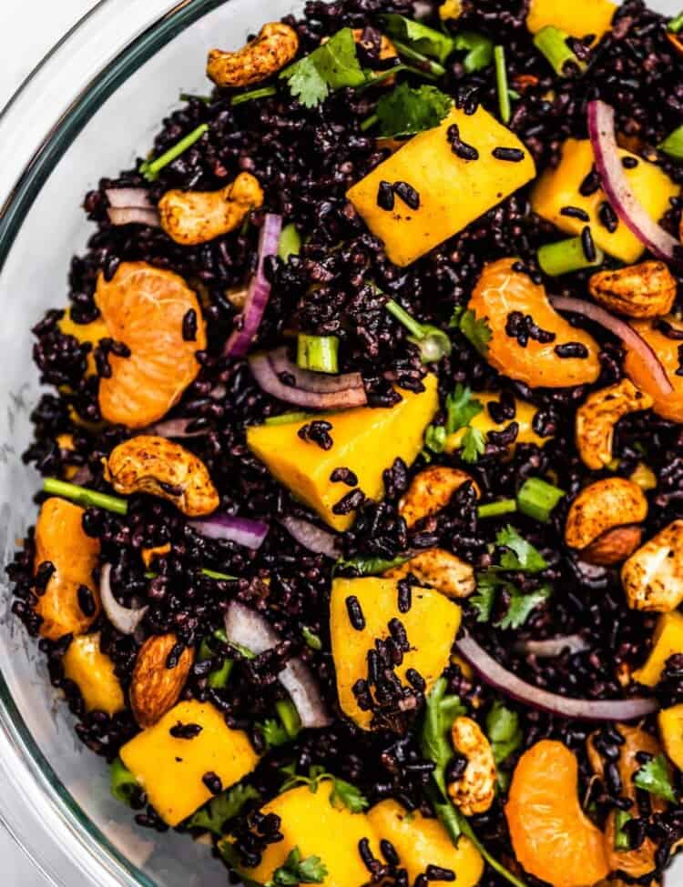 A close up of black rice salad with mango and cashews.
