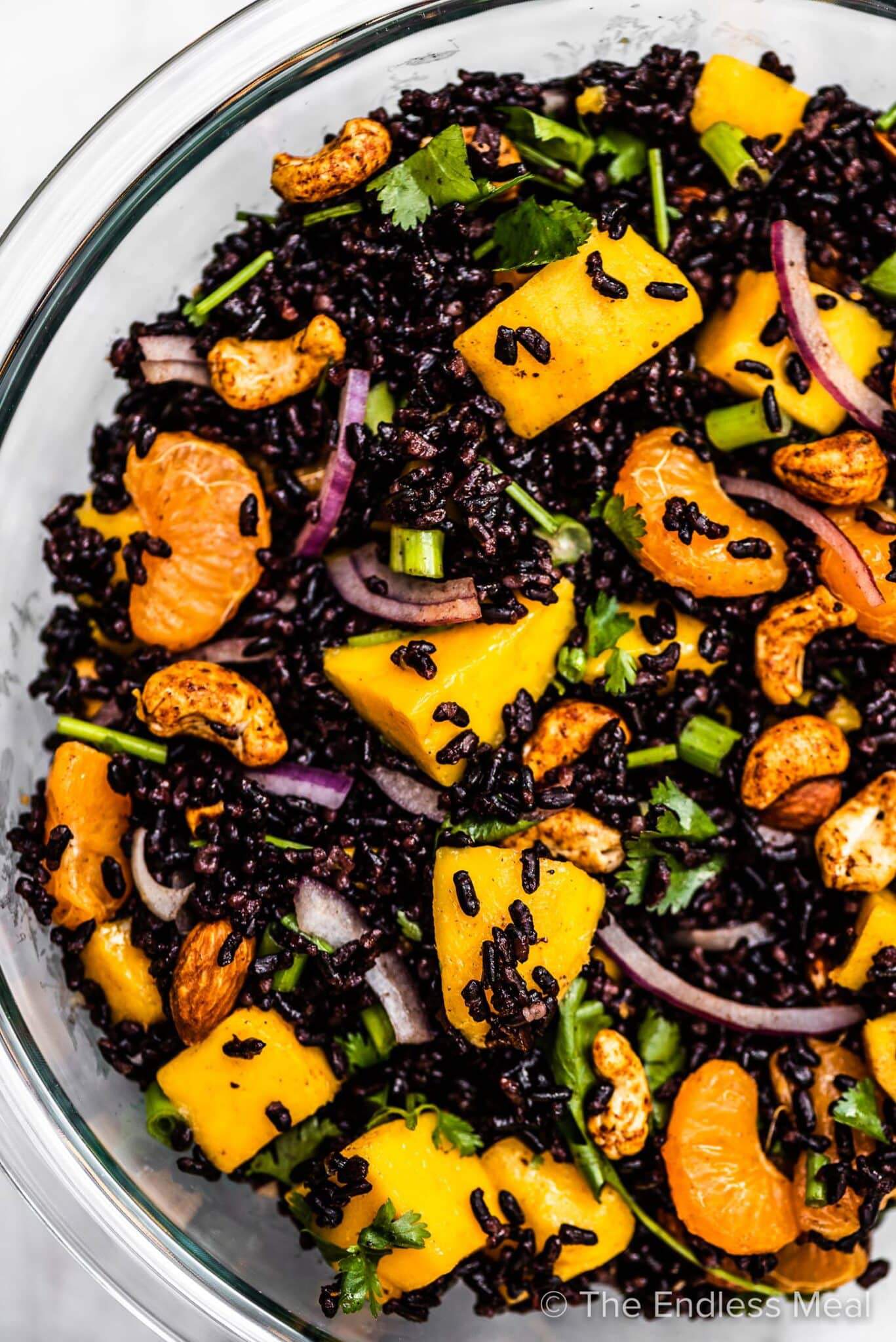 A close up of black rice salad with mango and cashews.