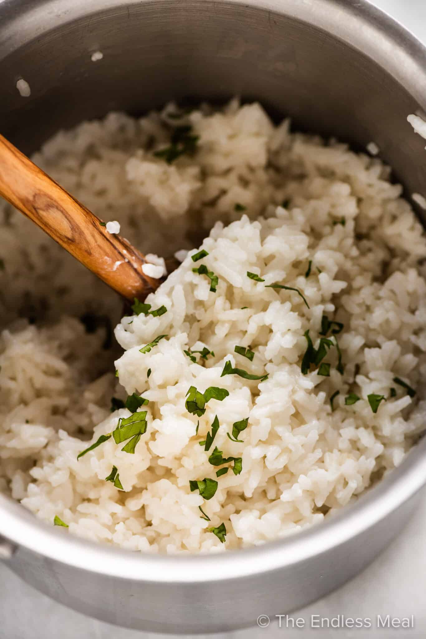 Coconut rice in a pot with a wooden spoon.