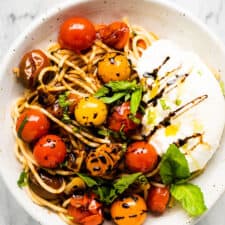Summer spaghetti in a white plate with burrata.