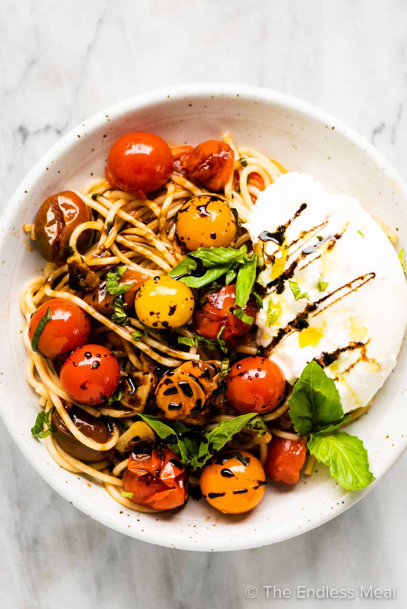 Summer spaghetti in a white plate with burrata.