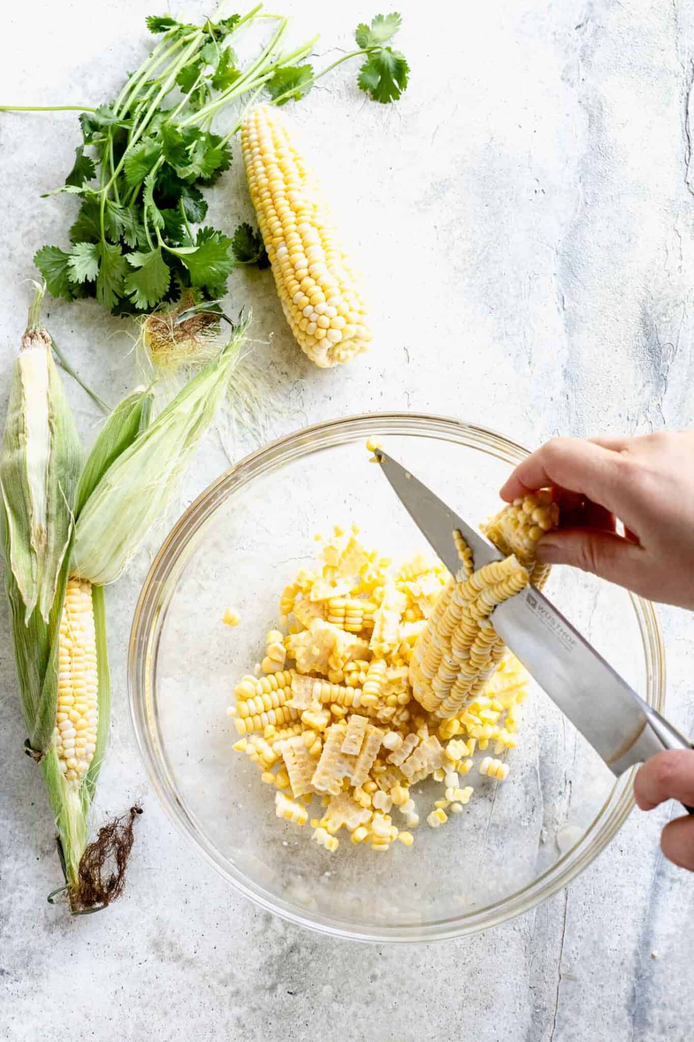 cutting the kernels off the cob into a bowl