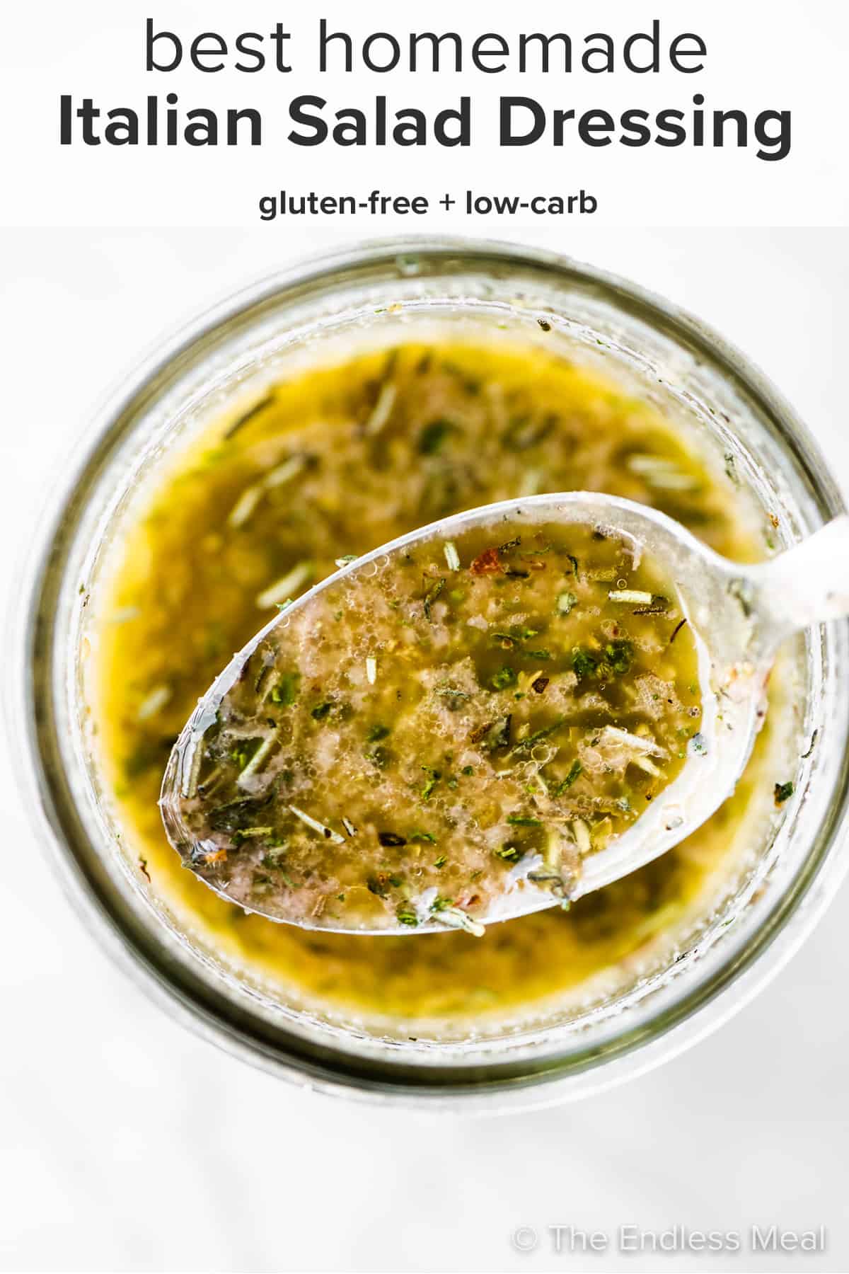 A spoon scooping some homemade italian dressing out of a jar and the recipe title on top of the picture. 