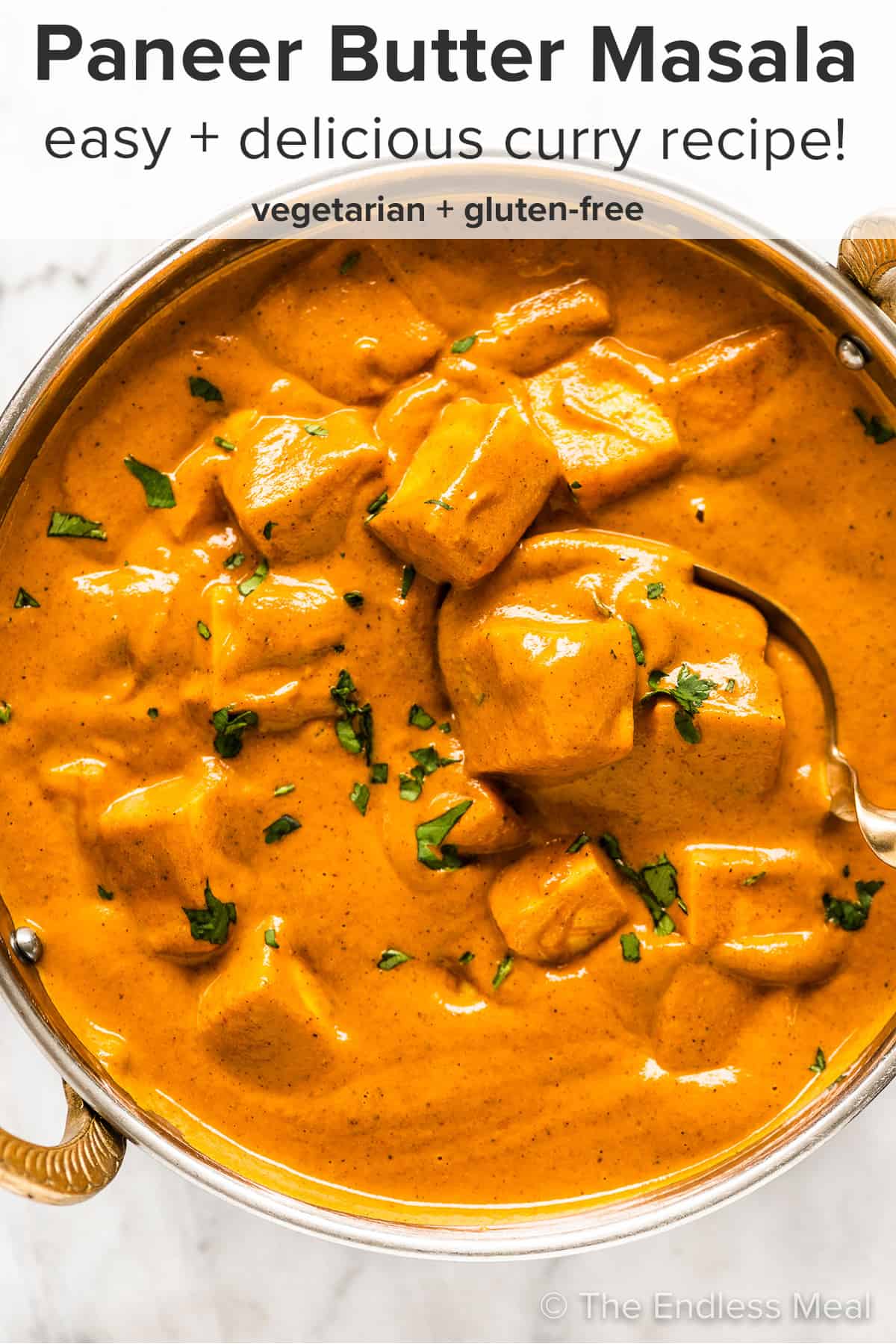 Paneer Butter Masala in a brass serving dish and the recipe title on top of the picture.