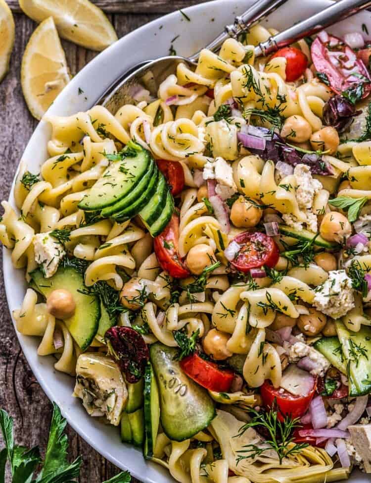 A close up of Greek pasta salad in a white bowl.