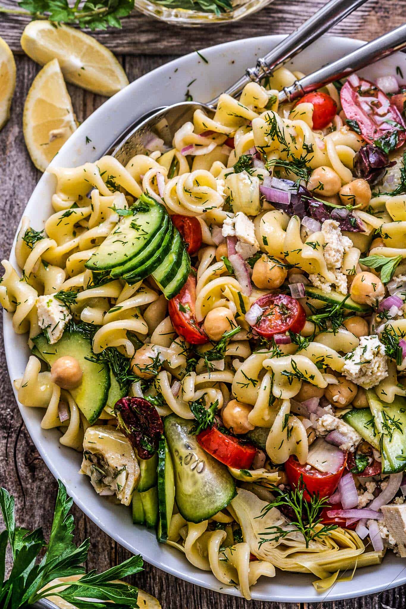 A close up of Greek pasta salad in a white bowl.