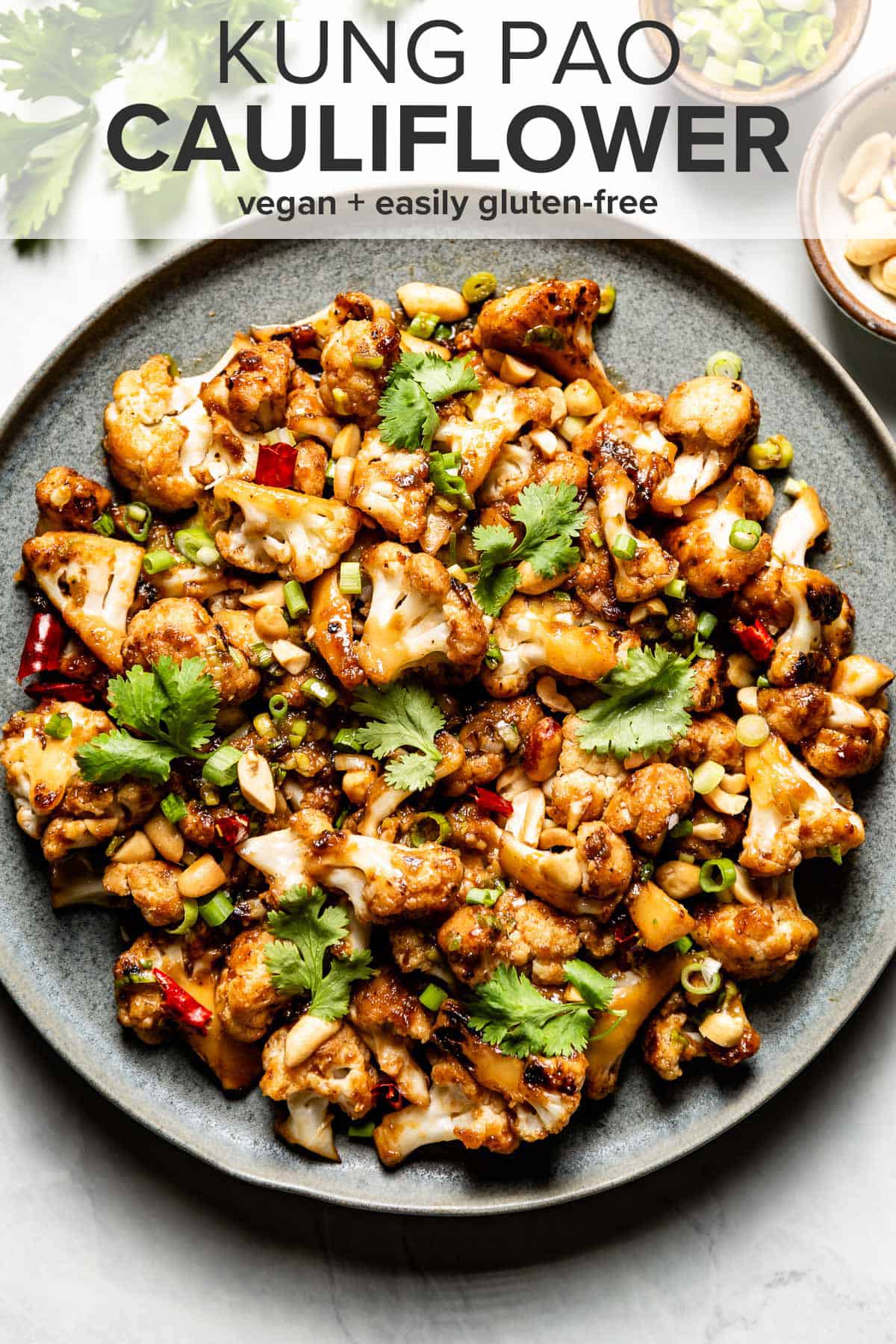 Kung Pao Cauliflower on a plate with two spoons on the side and the recipe title on top of the picture. 
