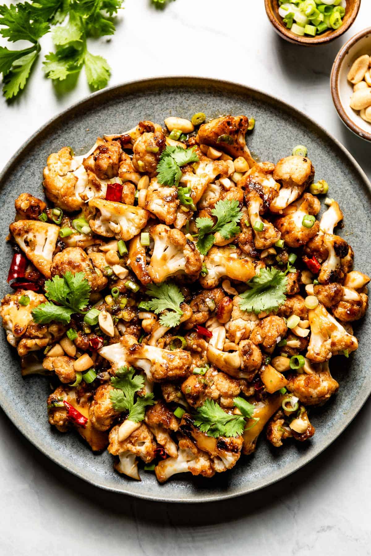 Kung Pao Cauliflower bites garnished with cilantro and peanuts from the top view