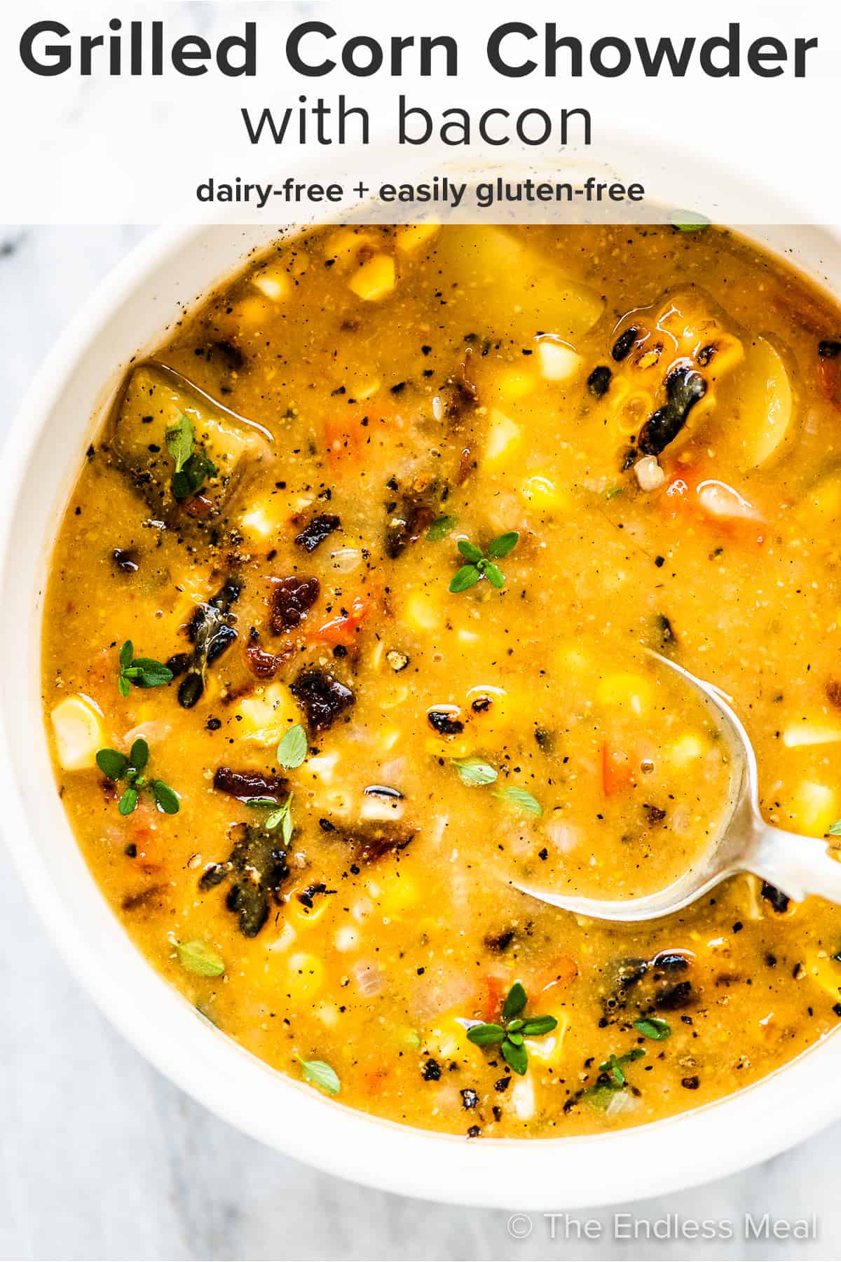 A bowl of grilled corn chowder with a spoon in it and the recipe title on top of the picture.