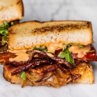 A bacon sandwich with lots of caramelized onions.