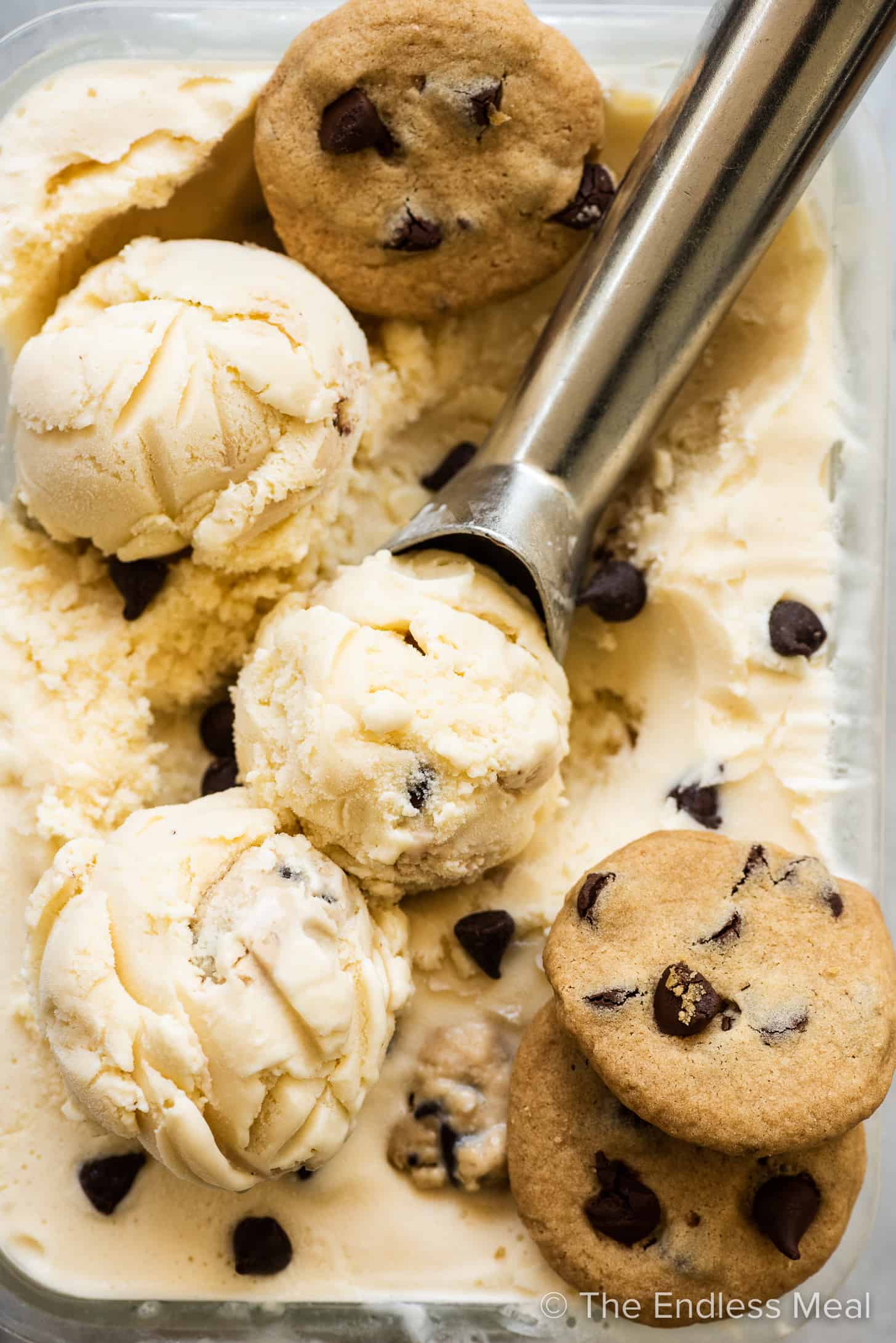 Chocolate Chip Cookie Dough Ice Cream with an ice cream scoop and three cookies. 
