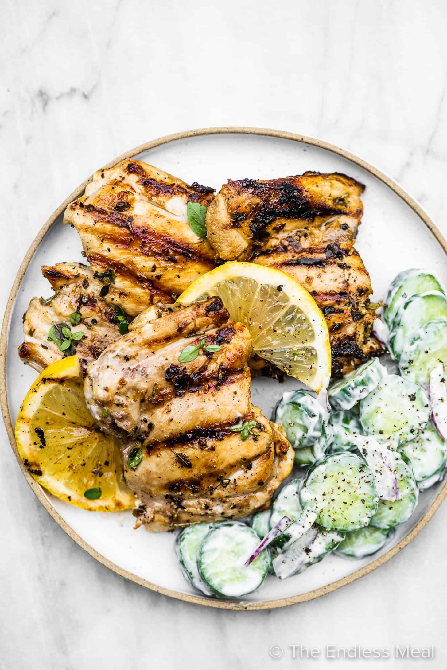 Grilled lemon garlic chicken on a plate with cucumber salad.