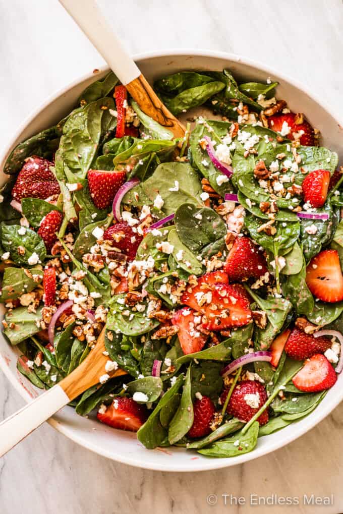 Strawberry Spinach Salad in a serving bowl with tongs.
