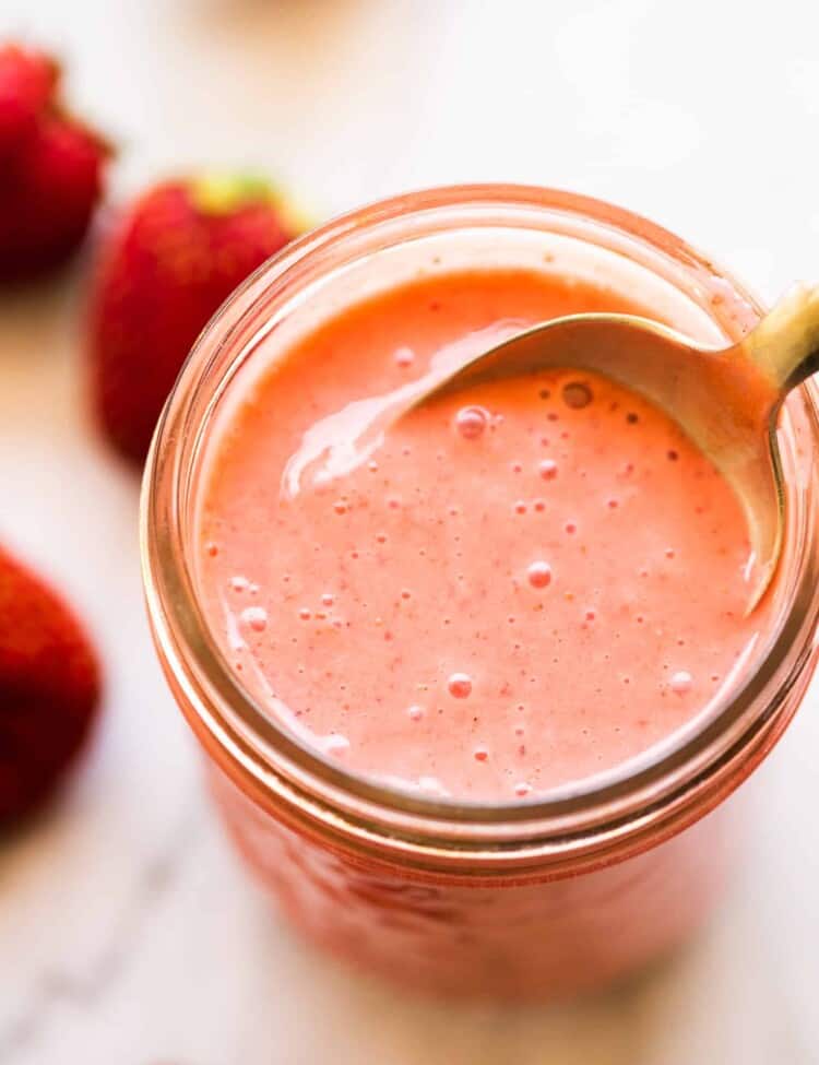 Strawberry vinaigrette in a glass jar with a spoon.