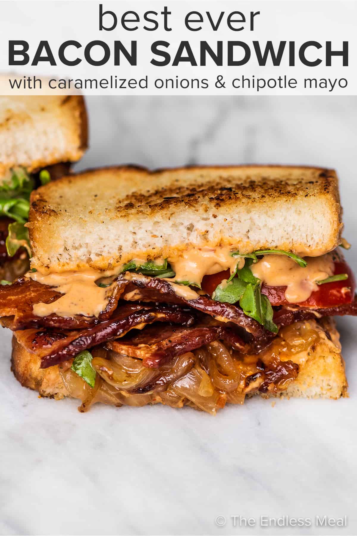 A bacon sandwich with lots of caramelized onions and the recipe title on top of the picture.