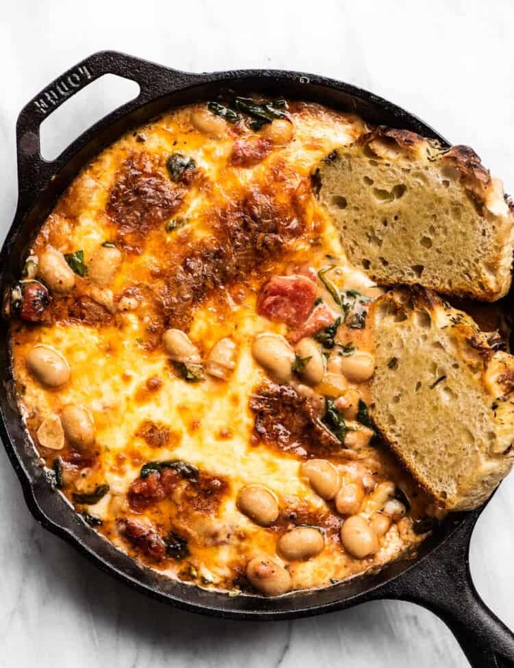 Cheesy White Bean Tomato Bake in a cast iron pan with bread.