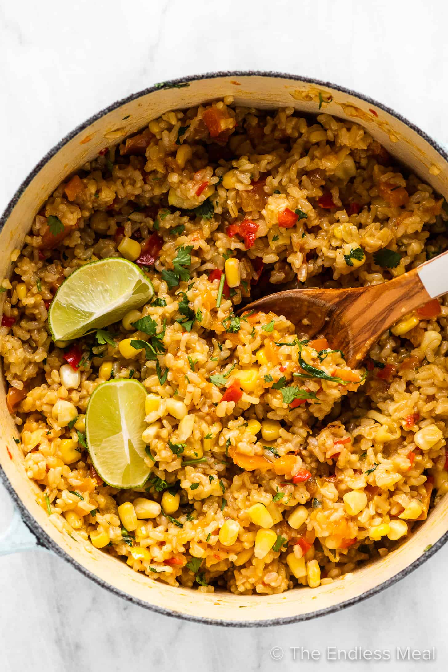 A pot of whole grain Mexican rice with lime wedges on top.