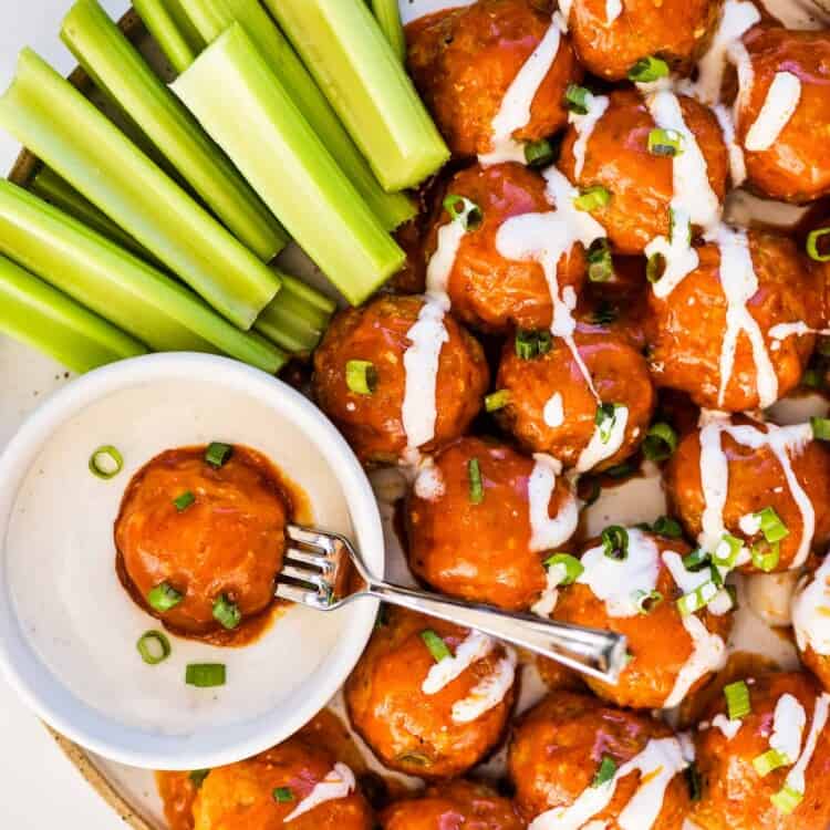 buffalo turkey meatballs with ranch dressing and celery sticks on a serving plate.