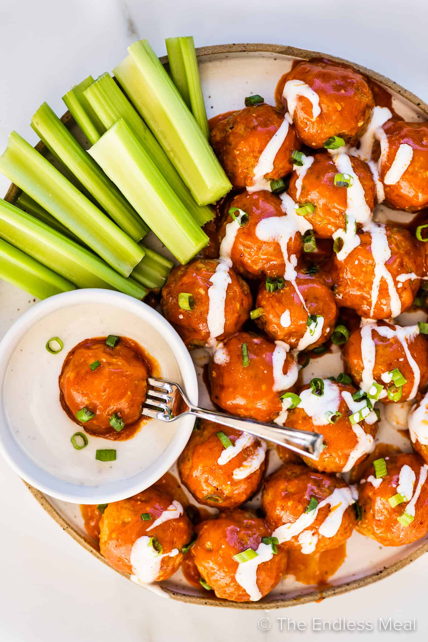 buffalo turkey meatballs with ranch dressing and celery sticks on a serving plate. 