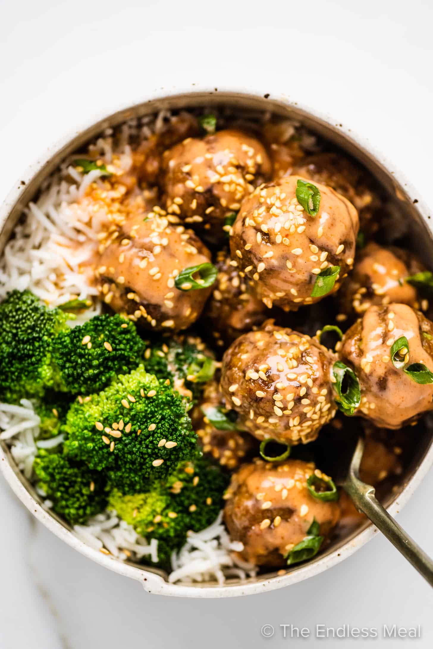 firecracker meatballs in a bowl with rice and broccoli.