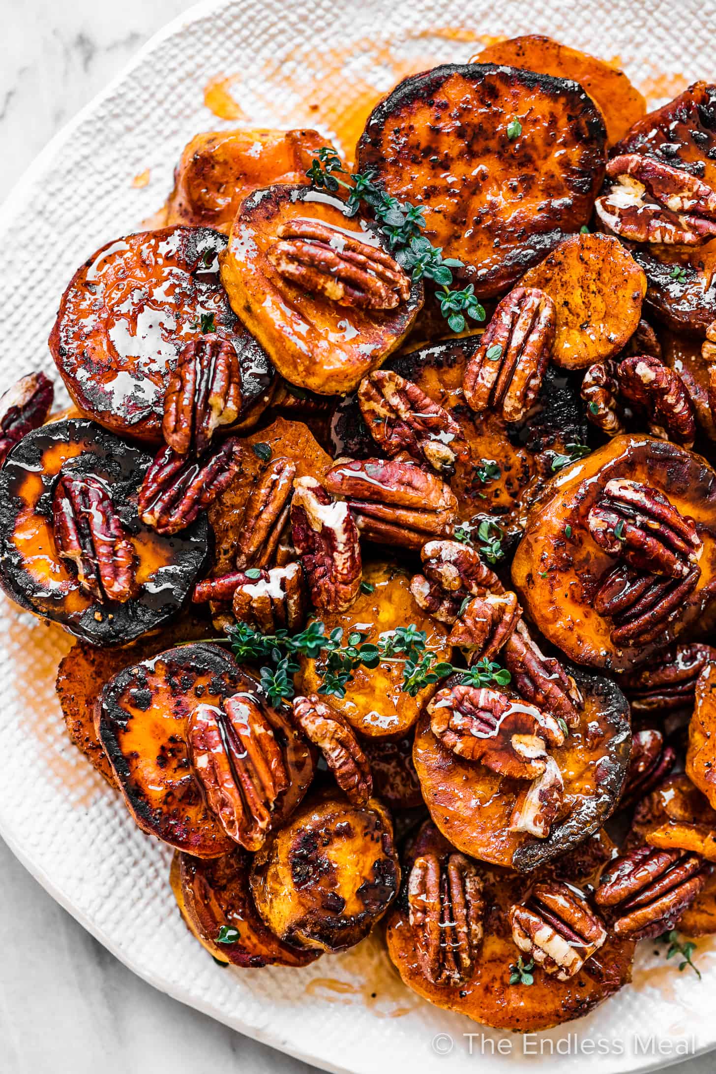 Hot honey roasted sweet potatoes and pecans on a serving plate. 