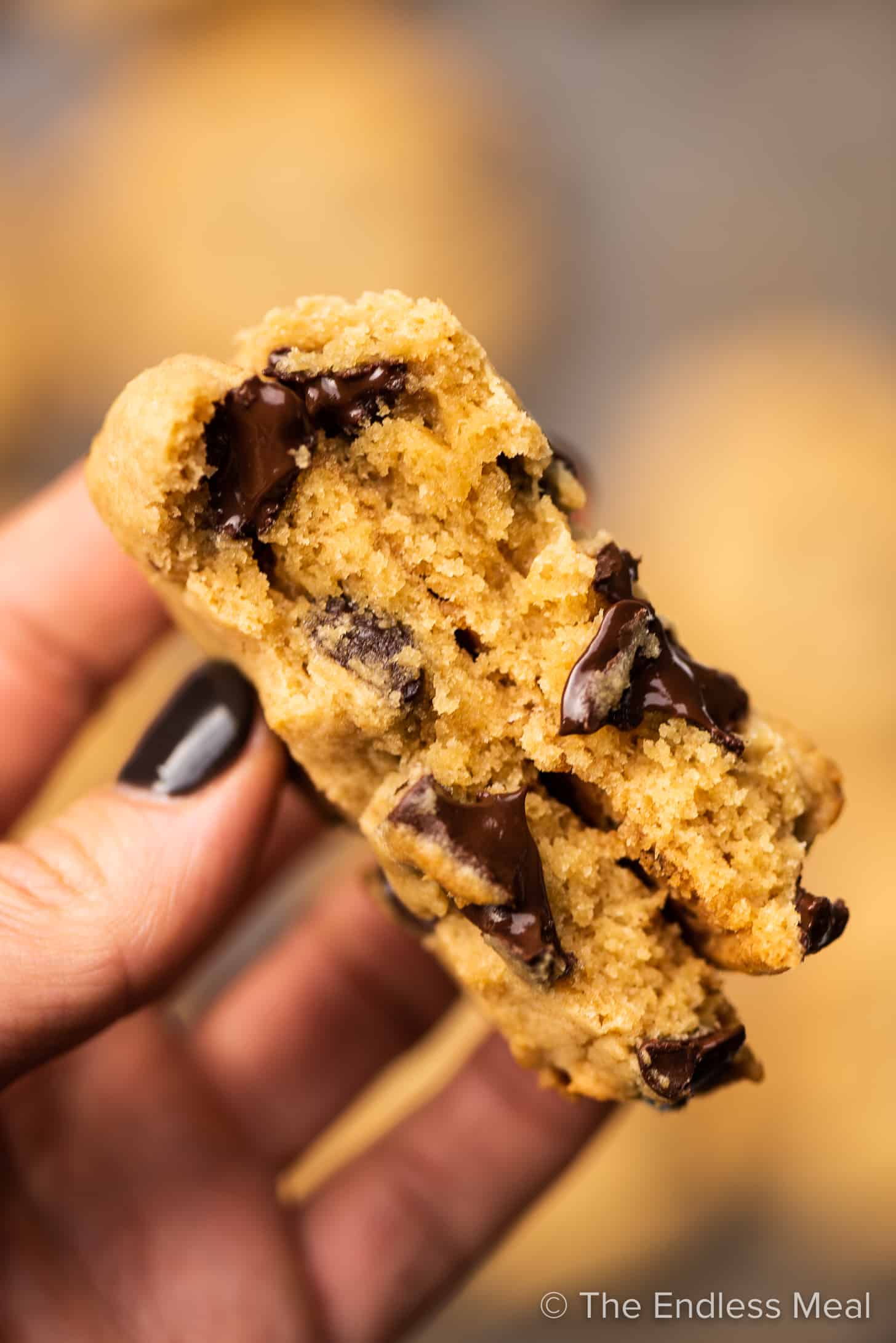 A hand holding a miso chocolate chip cookie that's broken in half. 