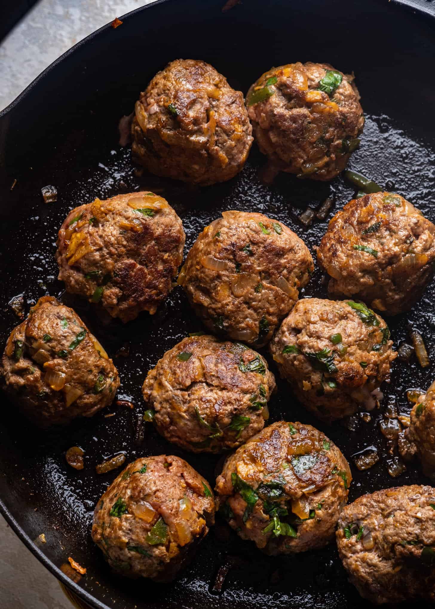 Tex-Mex Meatballs frying in a cast iron pan.