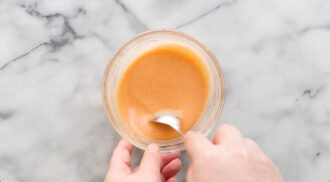 A hand stirring firecracker sauce.