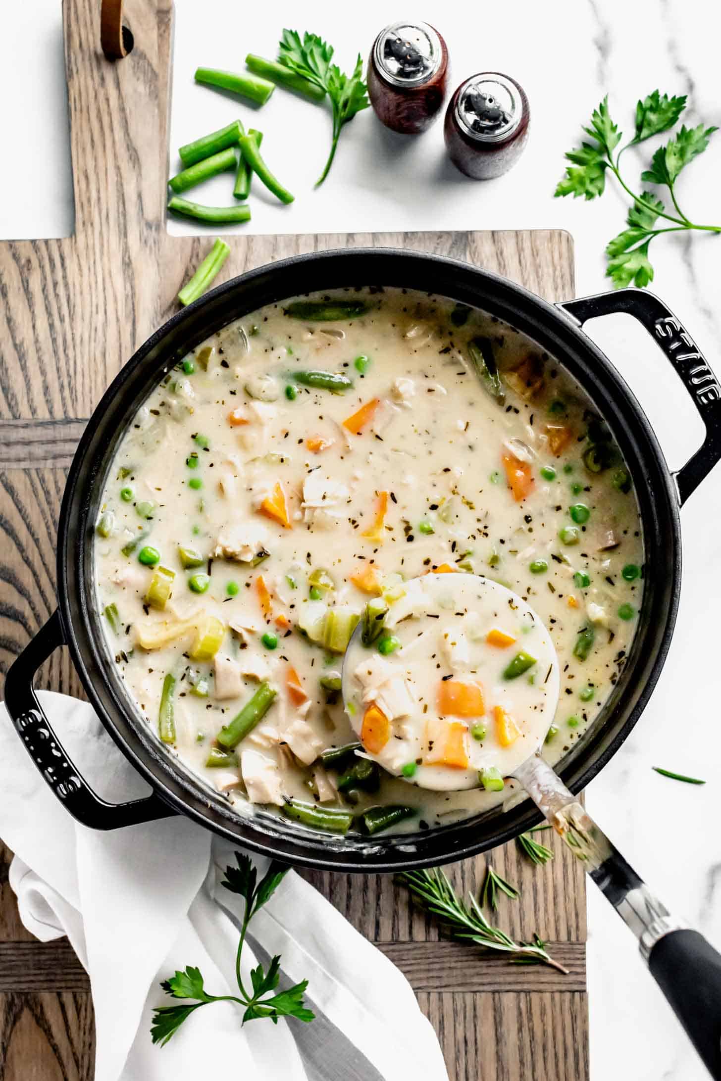 a pot of the turkey pot pie soup with a ladle full being lifted out