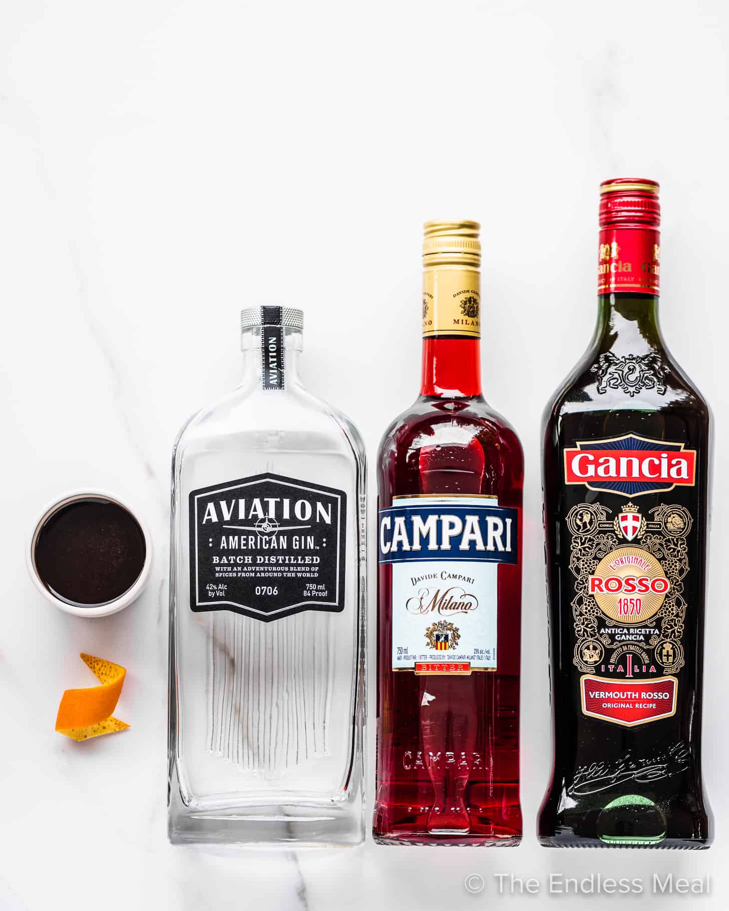 The ingredients to make a Coffee Negroni on a marble countertop.