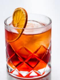 a mezcal negroni in a rocks glass with a dehydrated orange wheel.
